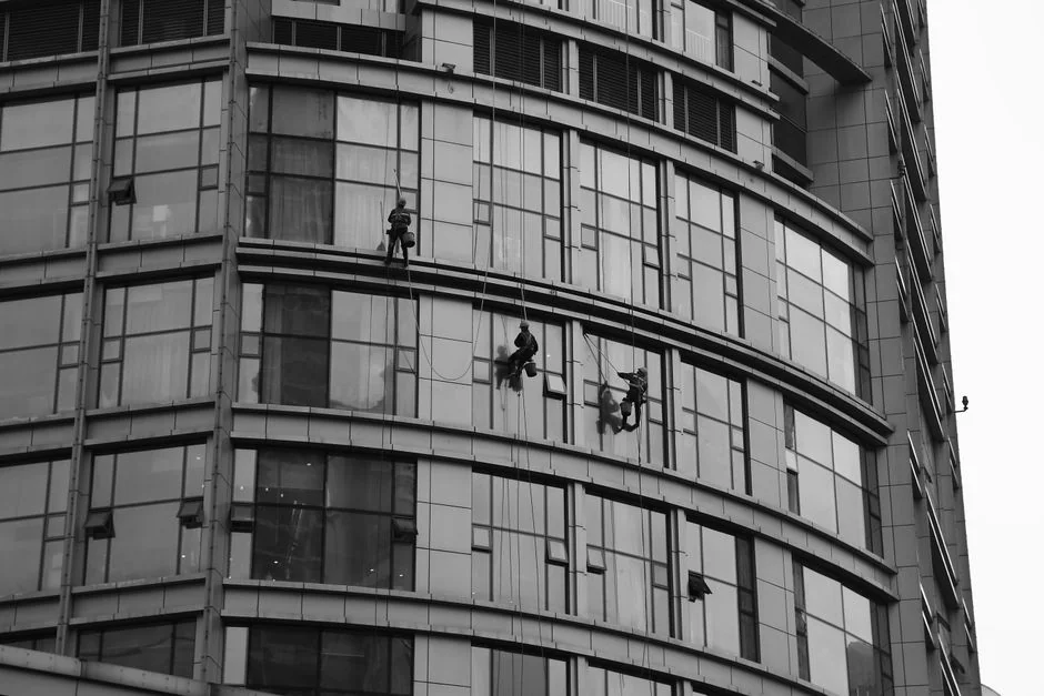 heros-img Deux employés nettoient les fenêtres d’une façade vitrée à l’aide d’une nacelle, ce qui améliore l’esthétique du bâtiment.